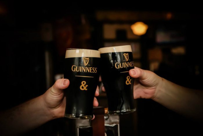 two people clinking together pints of Guinness