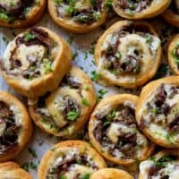 Philly Cheese Steak Pinwheels piled up on a baking sheet