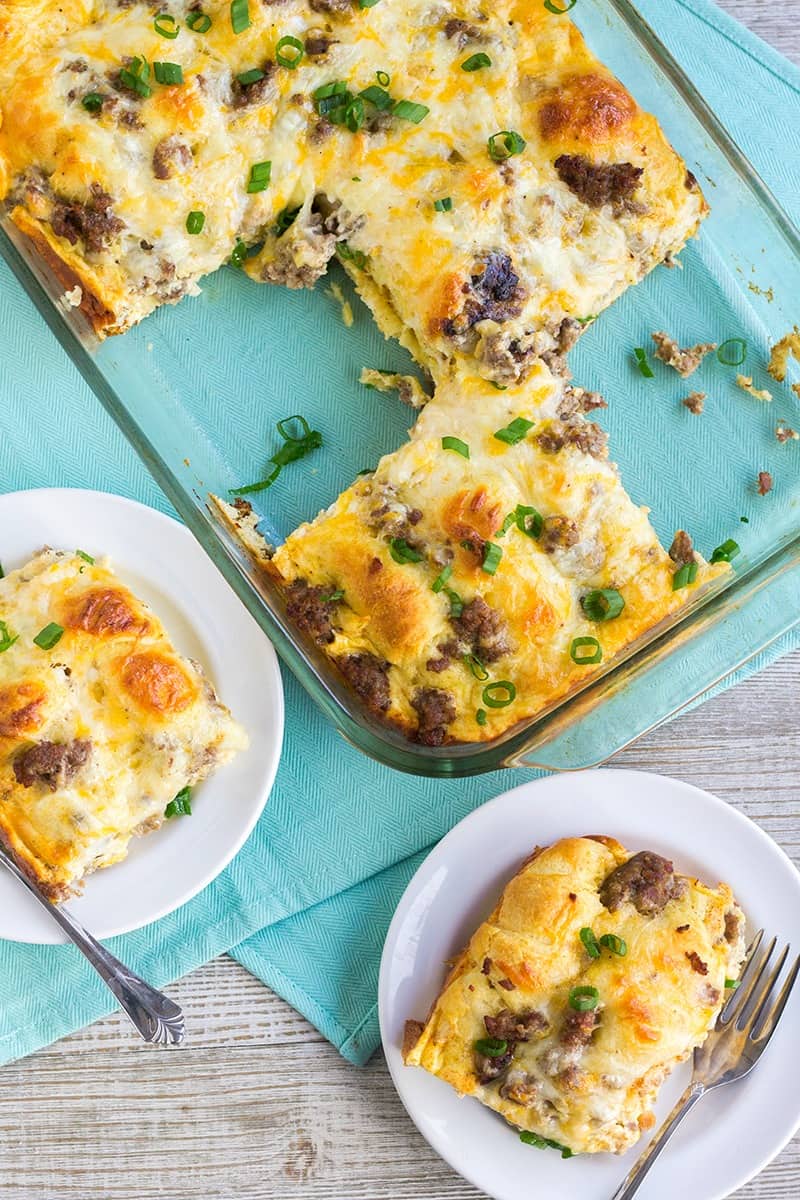 Cheesy Sausage Crescent Roll Breakfast Casserole in a baking dish with portions cut out and served on plates