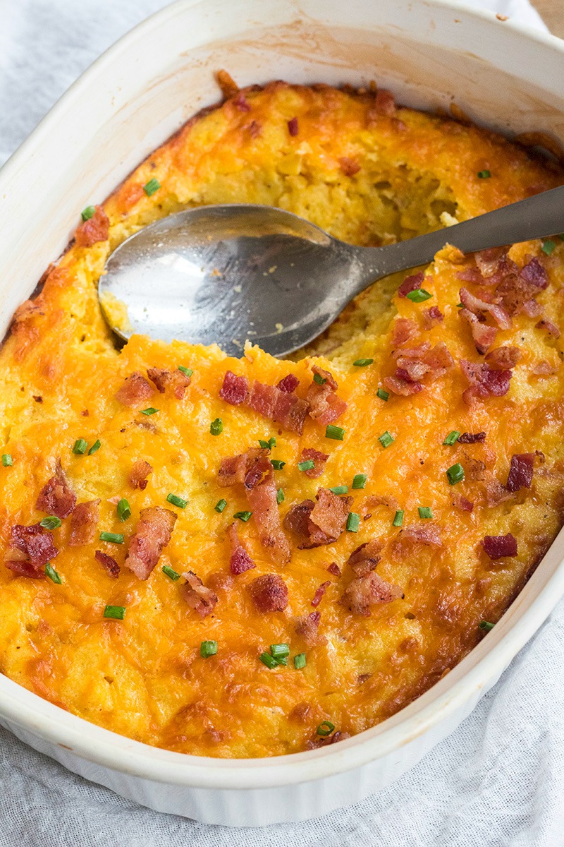 serving spoon resting in cheesy bacon spoon bread recipe dish after serving a portion