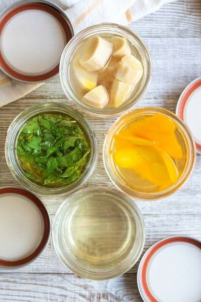 looking into mason jars of simple syrup while herbs, fruit, and spice infuse