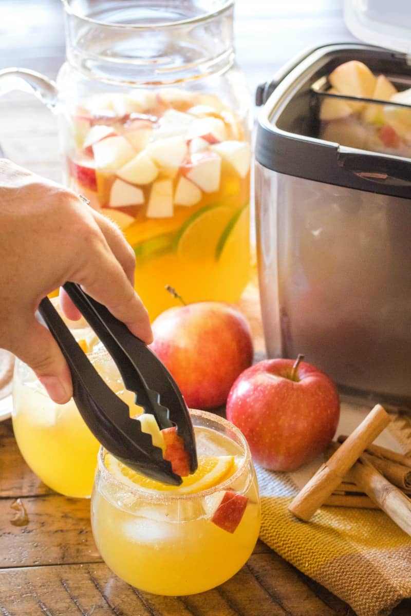 apples being added to sangria from OXO ice bucket with tongs