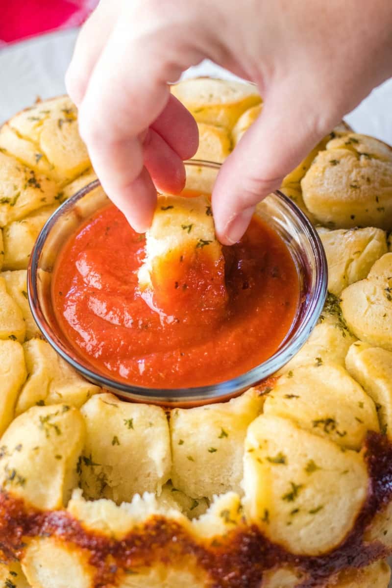 pull apart garlic bread being dipped in pizza sauce