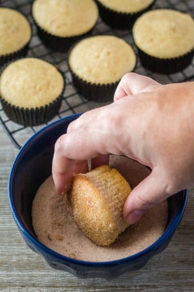 cinnamon muffin being dipped in cinnamon sugar