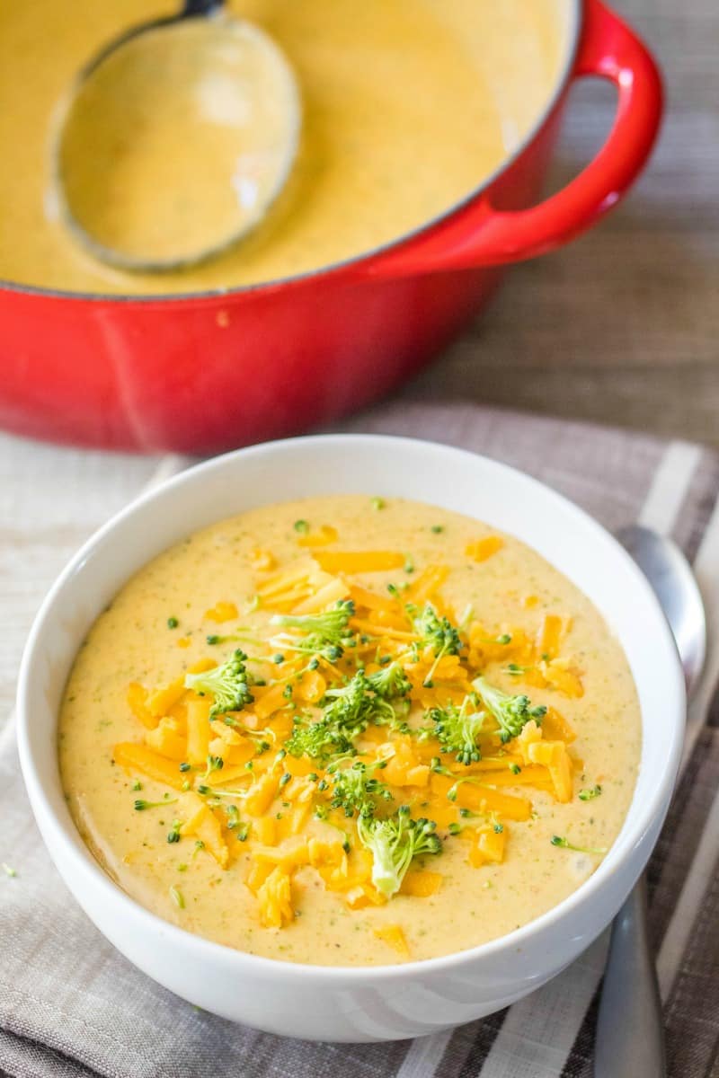 bowl of broccoli cheese soup with a pot of soup in the background