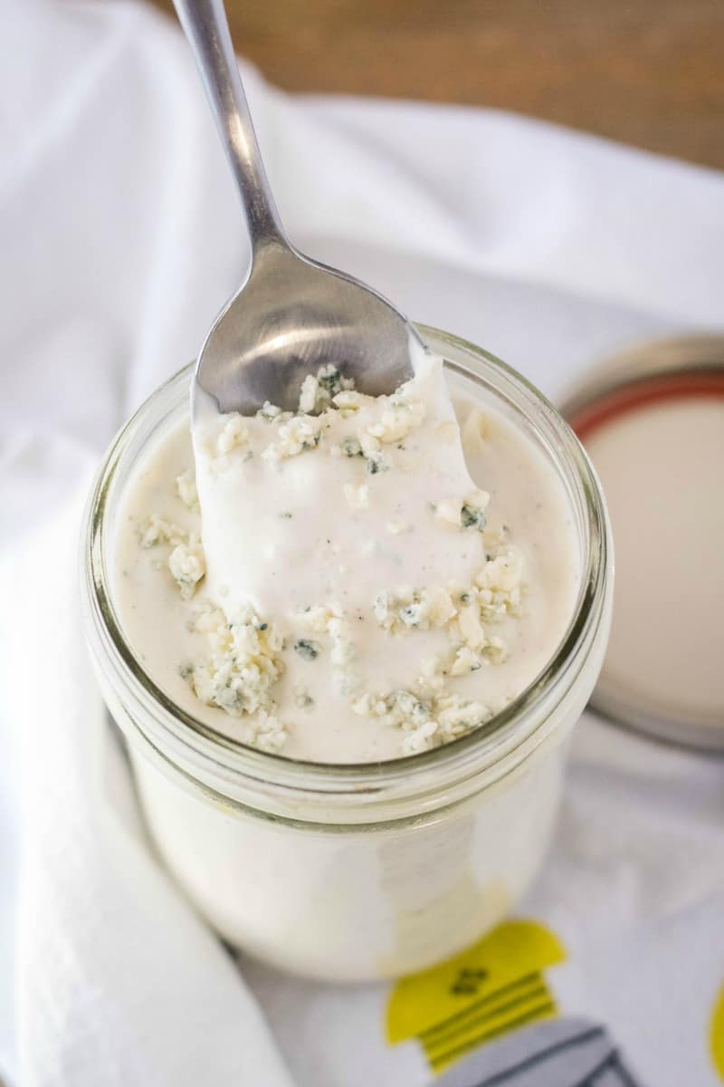 spoon scooping blue cheese dressing out of a mason jar