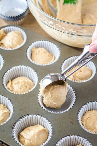 banana bread muffin batter being scooped in to muffin tin