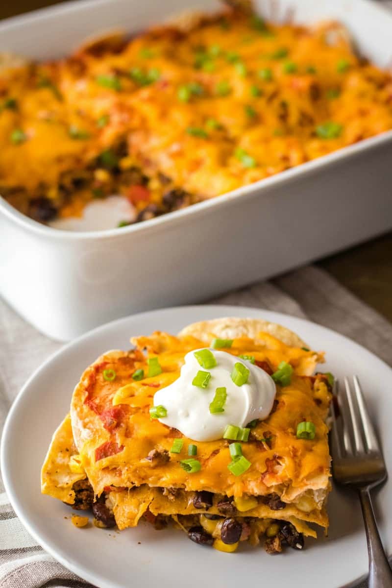 mexican lasagna recipe served on a plate with sour cream and green onion