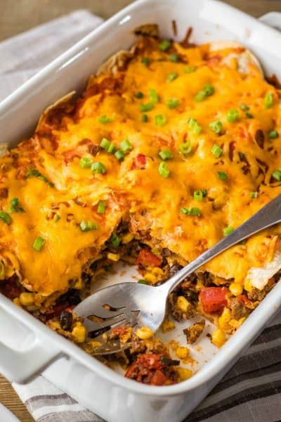 mexican lasagna in a baking dish with a portion taken out