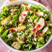 Craving a yummy salad? This easy Pomegranate and Pear Salad is drizzled with pomegranate vinaigrette and studded with goat cheese. It's great all by itself or topped with grilled chicken!