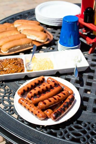 hot dogs, hot dog buns, and chili dog toppings on a patio table