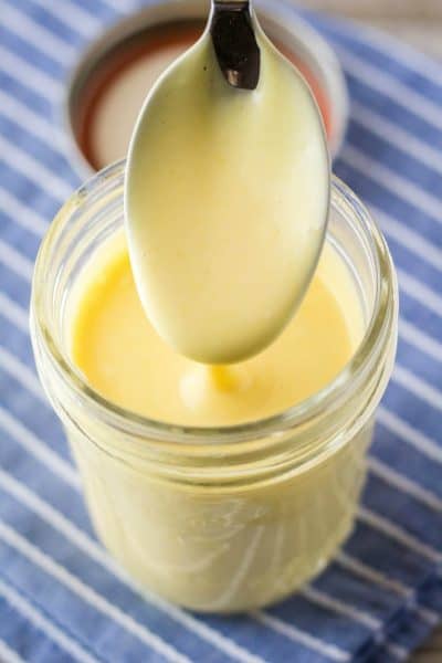 spoon covered in honey mustard dressing being lifted out of mason jar