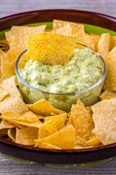 chip in a bowl of guacamole dip