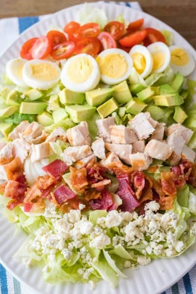 cobb salad on a platter with toppings lined up on lettuce