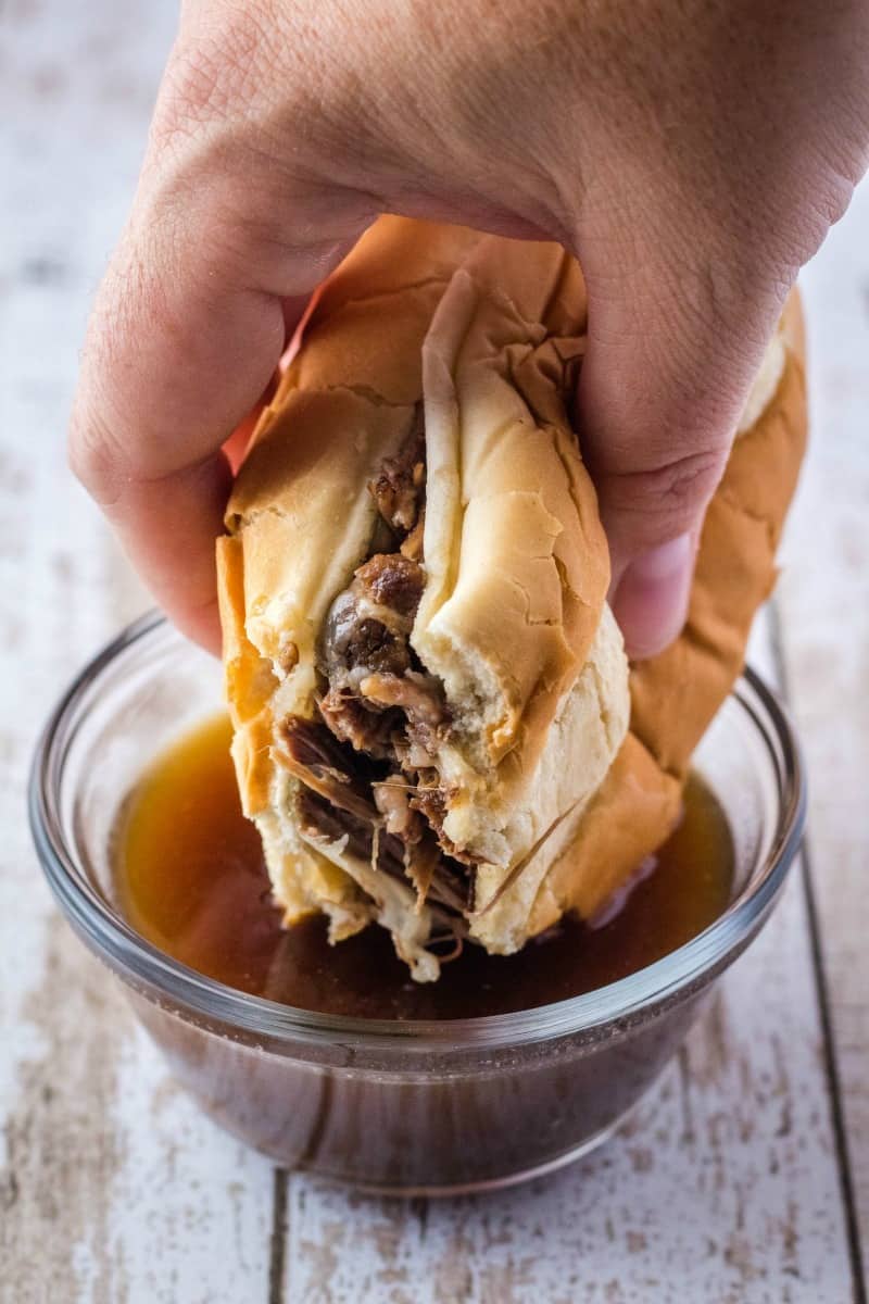french dip sandwich being dipped in au jus