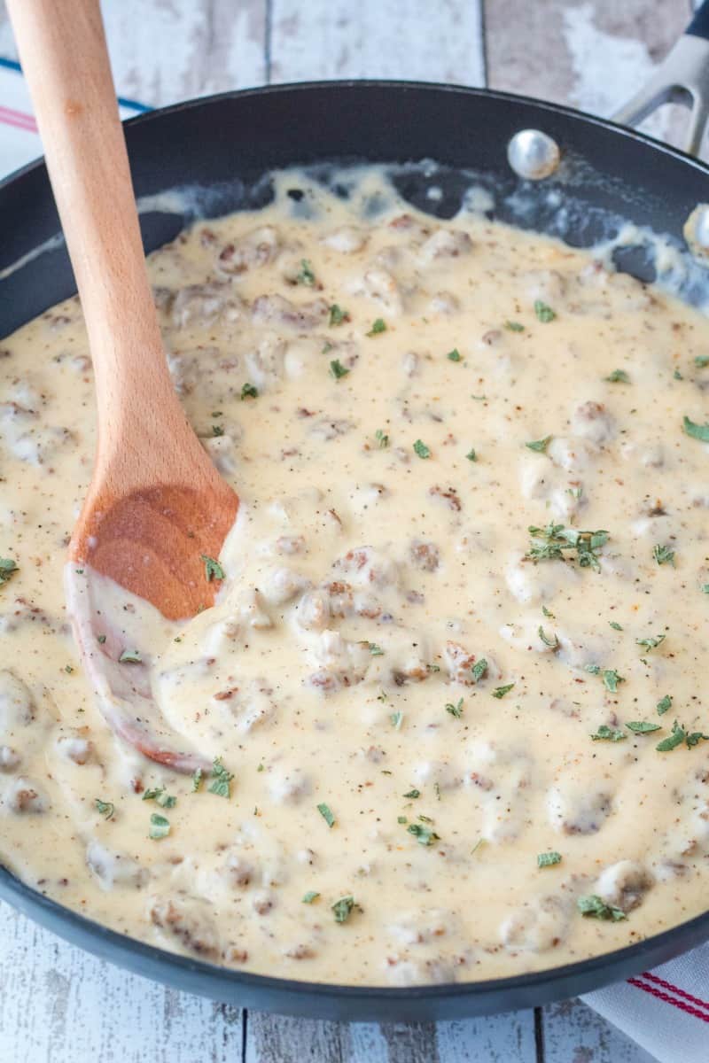 sausage gravy in a skillet topped with fresh sage