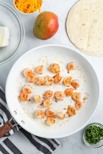 ingreidnets to make mango & shrimp quesadillas with cooked shrimp in a skillet