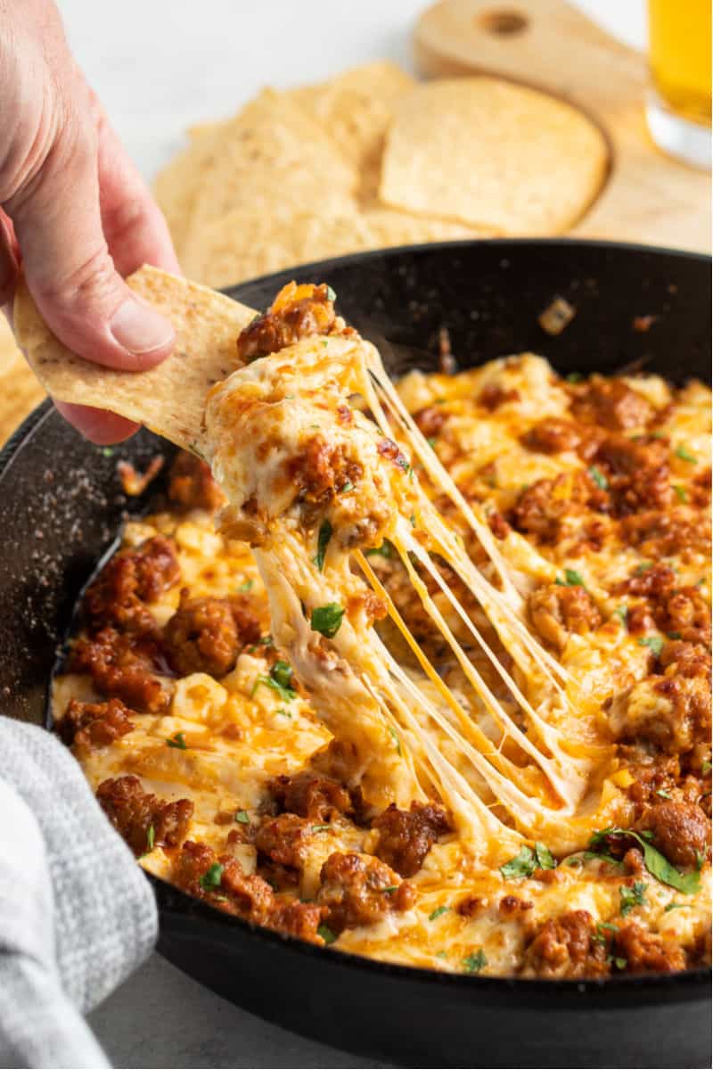 chip with a bite of chorizo queso fundido with lots of melted cheese