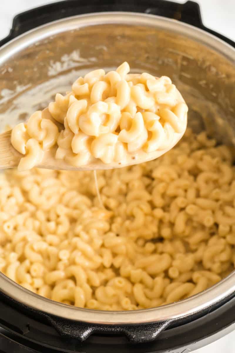 spoonful of mac and cheese over an instant pot with sauce dripping from the spoon