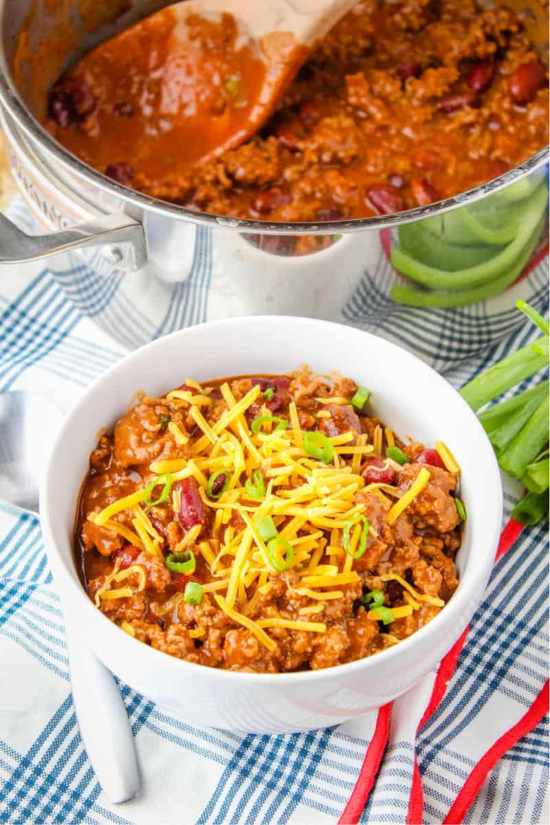 bowl of chili topped with cheese next to a pot of chili