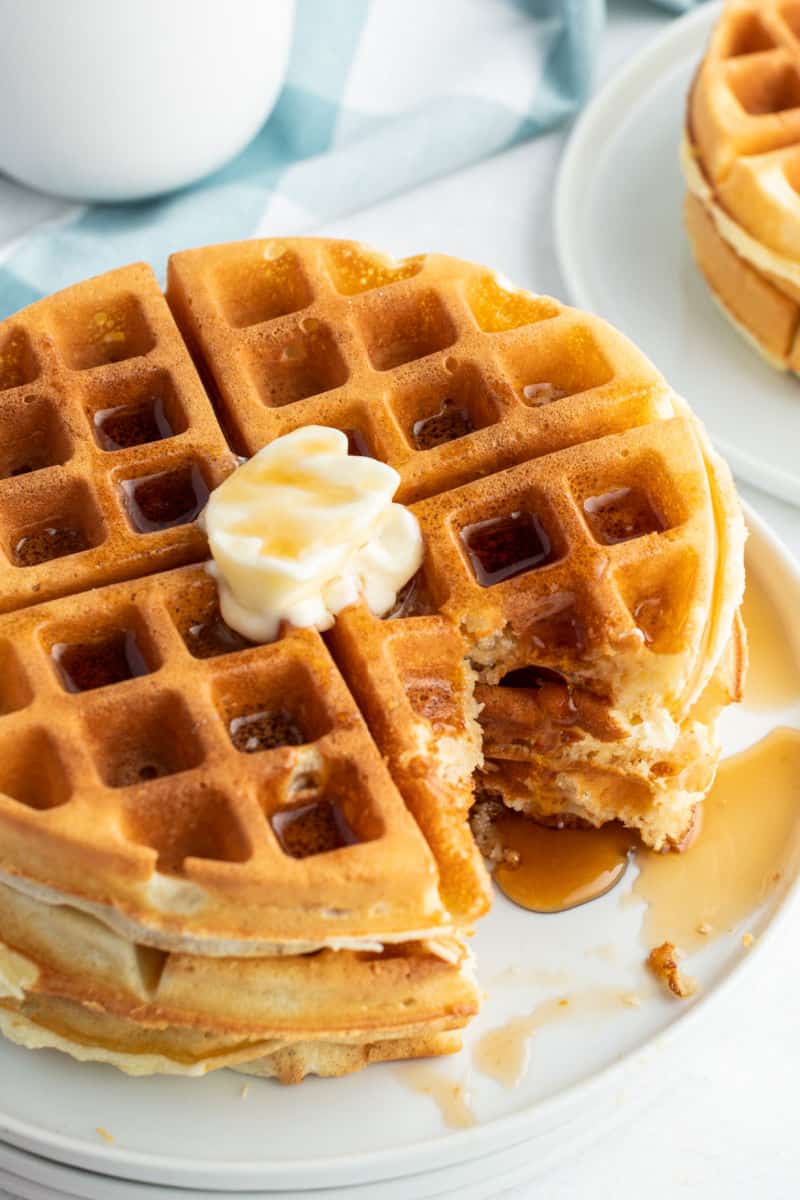 stack of waffles with butter and syrup with a portion cut out to show the texture
