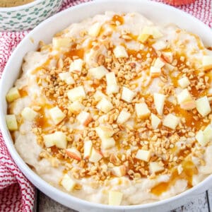 sqaure image fo caramel apple cheesecake dip topped with caramel, nuts, and fresh apples