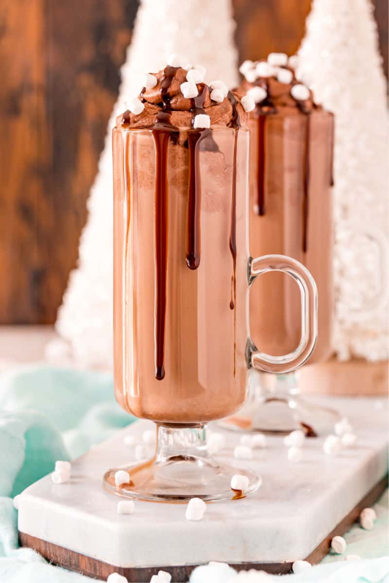 whipped hot chocolate in a tall handled glass with chocolate sauce running down the side