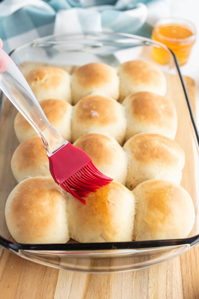 pastry bursh brushing melted butter onto the tops of dinner rolls