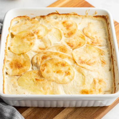 square image of scalloped potatoes in a baking dish with golden top