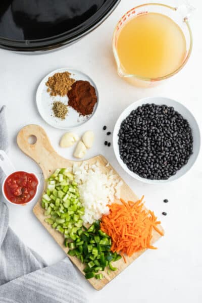 ingredients to make black bean soup laid out on a countertop next to a slow cooker