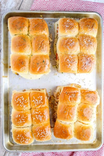 looking down at four types of chicken sliders on a baking sheet with seasonings on top