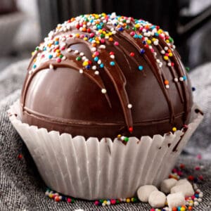 square image of a hot chocolate bomb in a cupcake liner with rainbow sprinkles on top