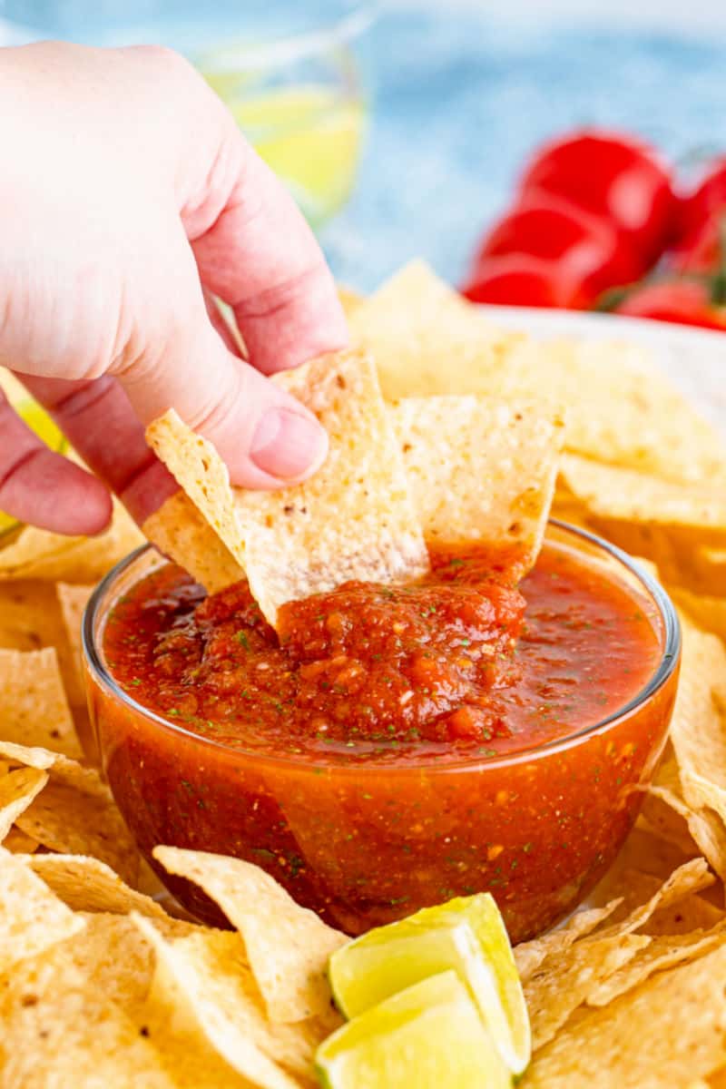 hand dipping chips into a bowl of blender salsa