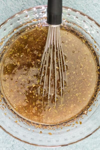 pasta salad dressing in a glass bowl with a whisk