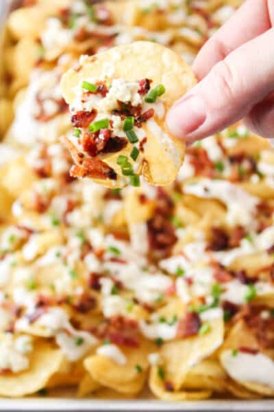 fingers holding a potato chip nacho to show toppings