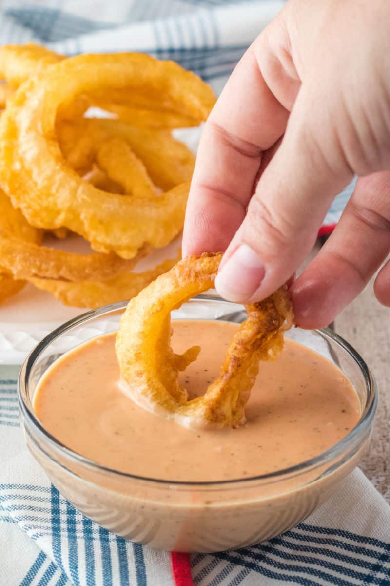 onion ring being dipped into fry sauce