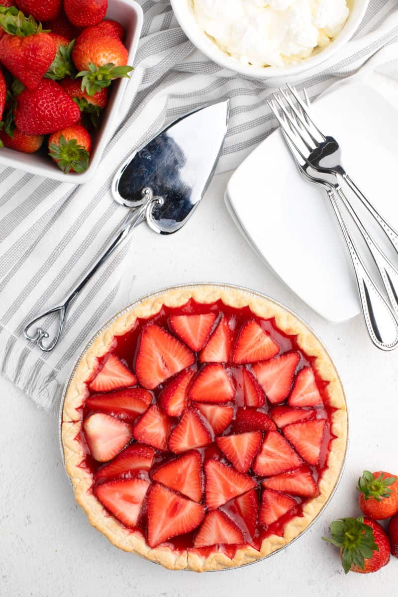 strawberry jello pie after chilling with pie server and bowl of whipped cream