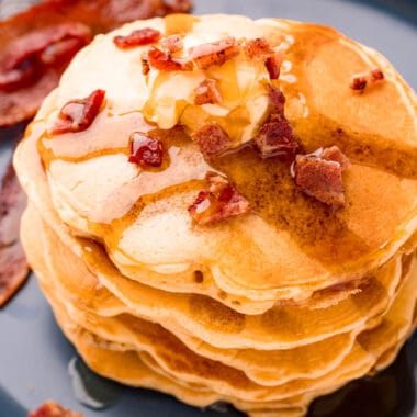 square image of bacon pancakes with butter, syrup, and crumbled bacon on top