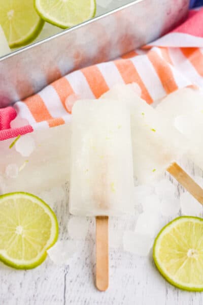 limeade popsicles stacked together next to lime slices