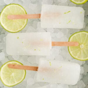 square image of limeade popsicles on a bed of ice with lime slices