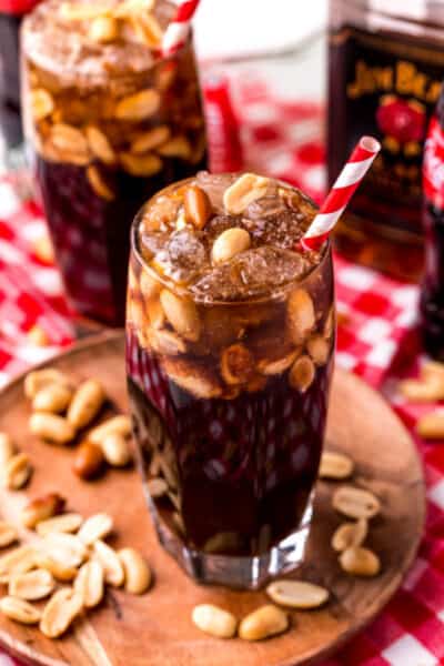 tall glass of coke and peanuts with bourbon and a red striped straw