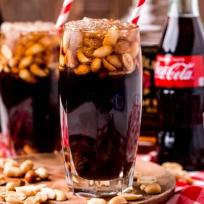 square image of peanuts and coke in glasses with straws