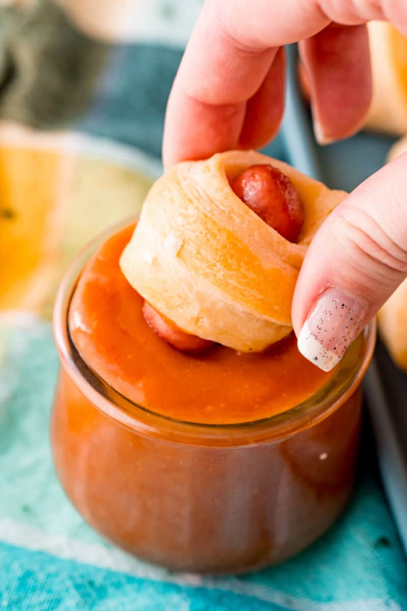 cheddar pigs in a blanket being dipped in sauce