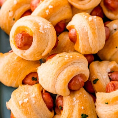 square image of cheddar pigs in a blanket piled on a paltter
