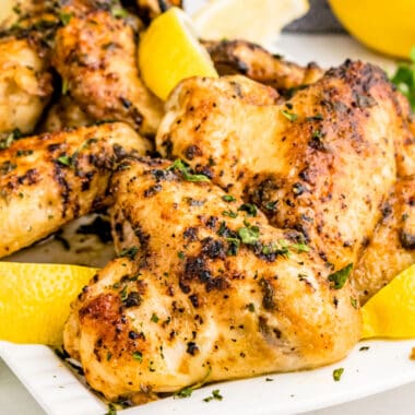 square image of air fryer lemon pepper chicken wings with parsley and lemon wedges