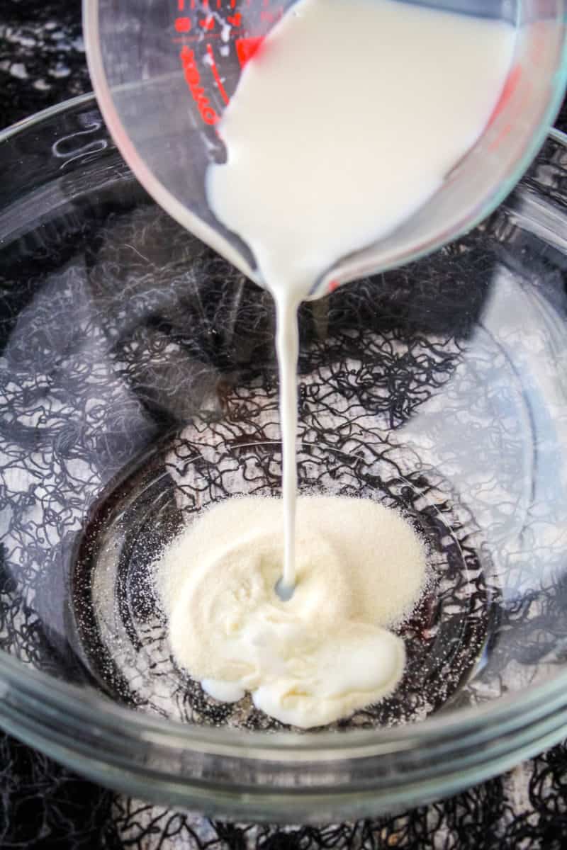 cold milk being poured onto gelatin powder in a bowl