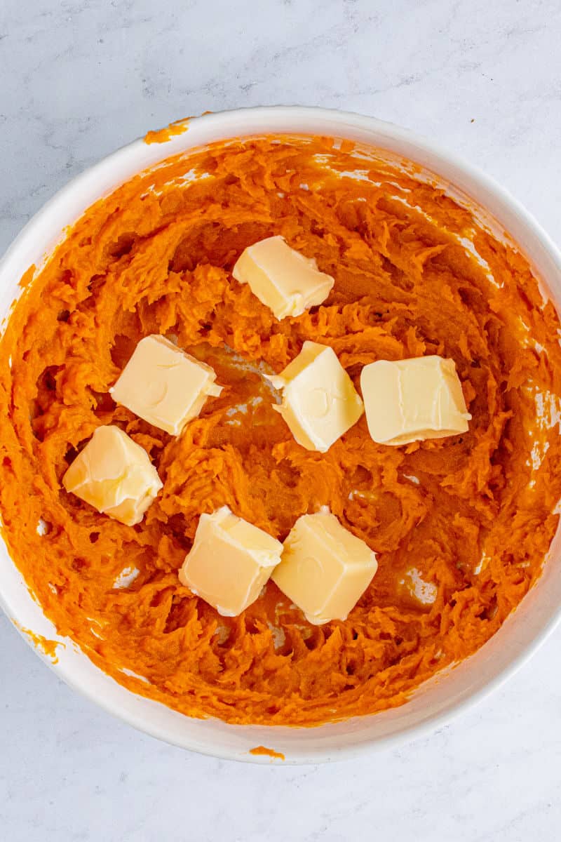 whipped sweet potatoes in a mixing bowl with butter