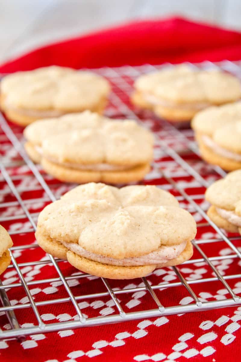 close up of cinnamon spritz sandwich cookies on a wire rack after being assembled