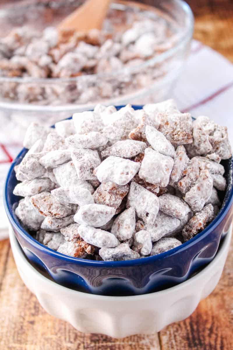 puppy chow muddy buddies in a small bowl stacked with another bowl