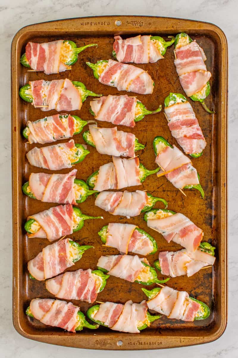 sheet pan with uncooked bacon wrapped jalapeno poppers